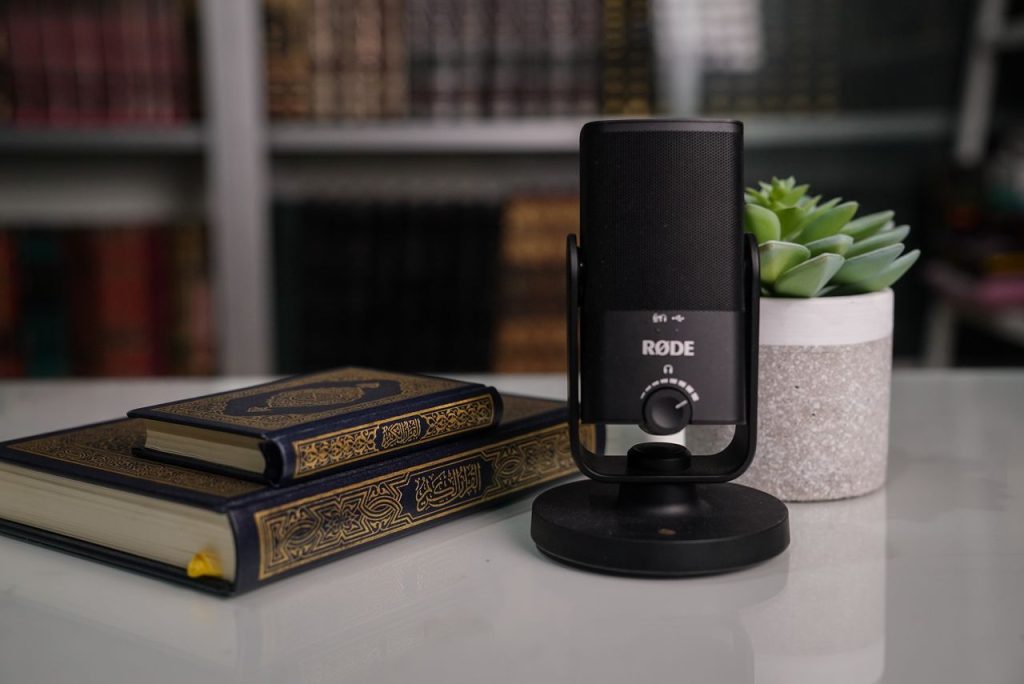 Close-up of books with a Røde microphone and succulent on a desk.